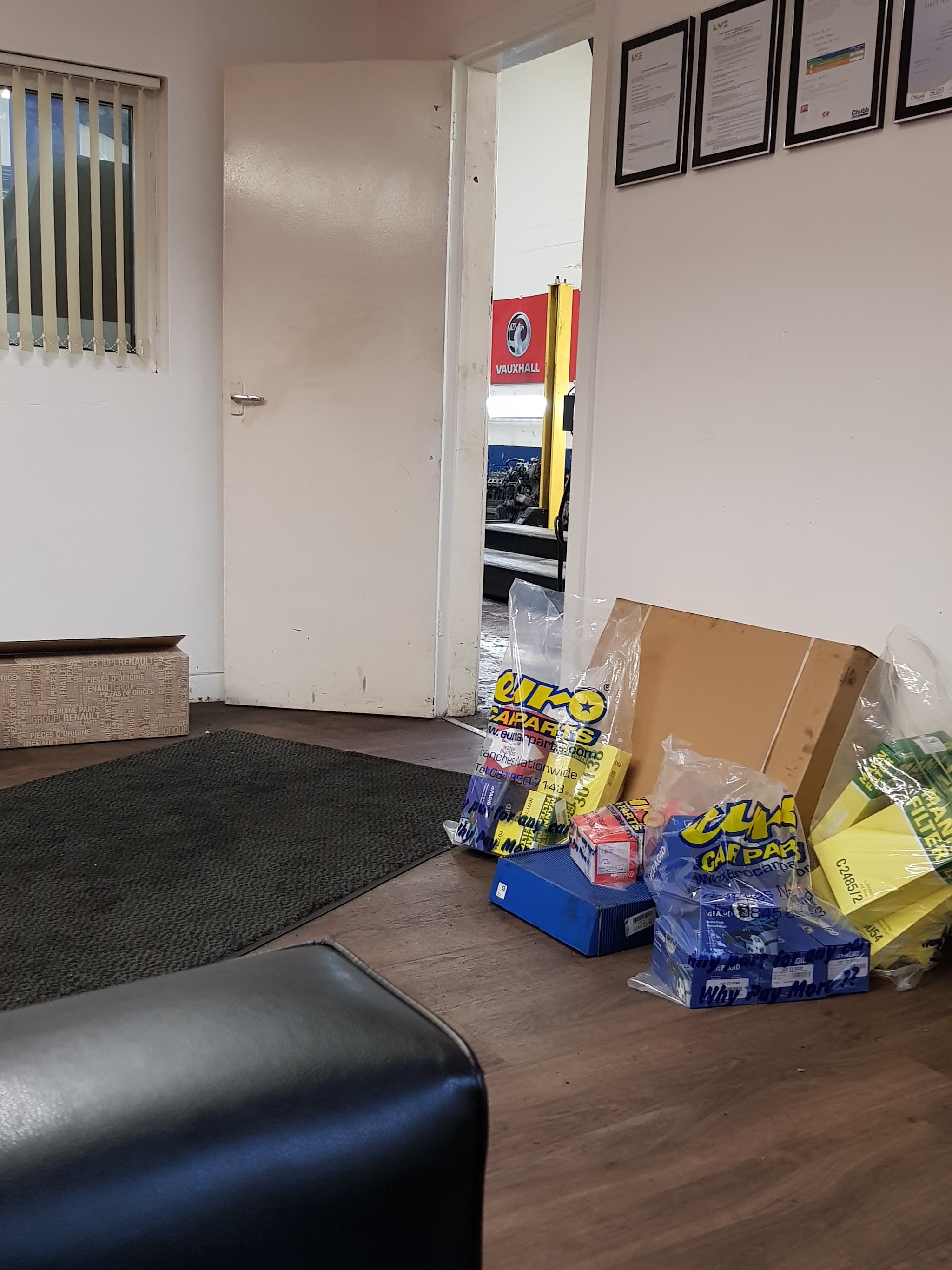 Reception room at All Vaux All looking through to a workshop ramp and a red Vauxhall sign